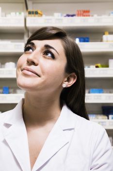 Smiling pharmacist looking up in a pharmacy