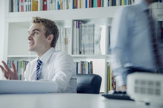 Young businessman discussing at a business meeting with colleague behind him