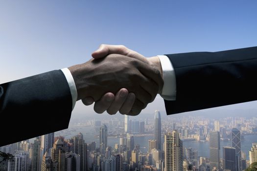 Close up of businessmen shaking hands with cityscape in the background