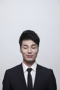 Relaxed young businessman with eyes closed, studio shot