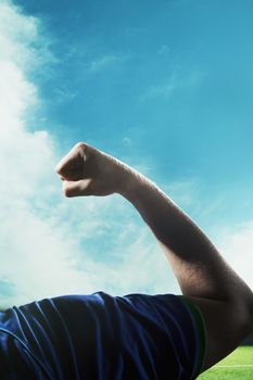 Soccer player flexing bicep during the day with sky in background