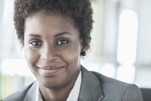 Portrait of smiling young businesswoman with short hair looking at the camera, head and shoulders