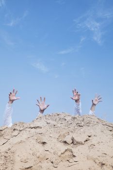 Close-up of hands of businessmen behind a hill in the desert, reaching upwards