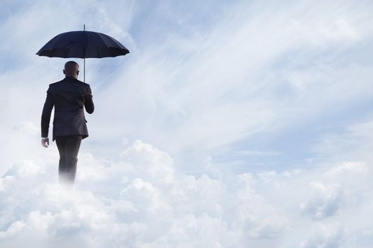 Businessman holding an umbrella and walking  away in dreamlike clouds