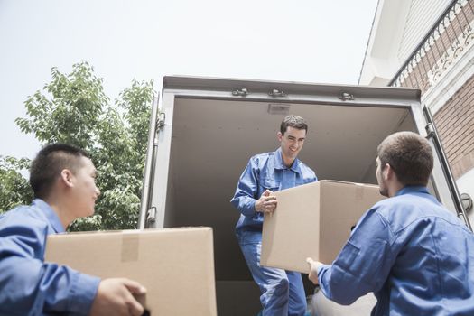 Movers unloading a moving van, passing a cardboard box