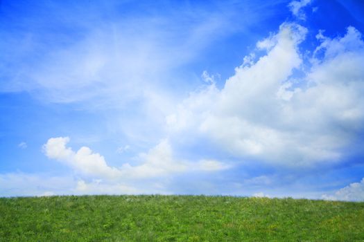 Lush, green landscape with blue sky and clouds.