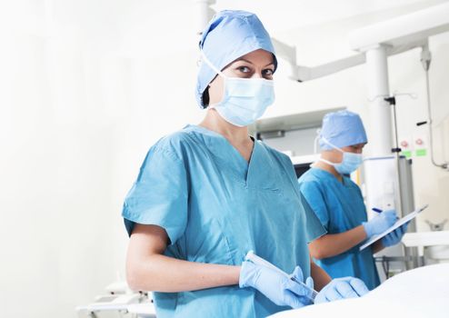 Female surgeon working in the operating room, looking at camera