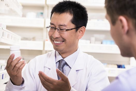 Smiling pharmacist showing prescription medication to a customer