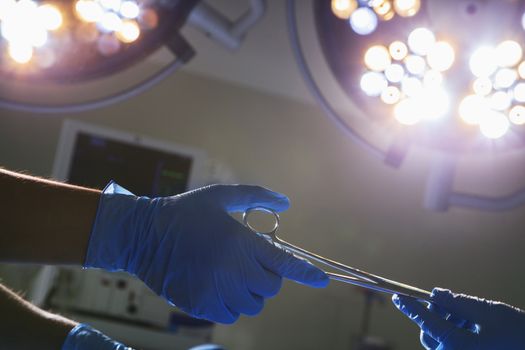 Close-up of gloved hands passing the surgical scissors, operating room, hospital