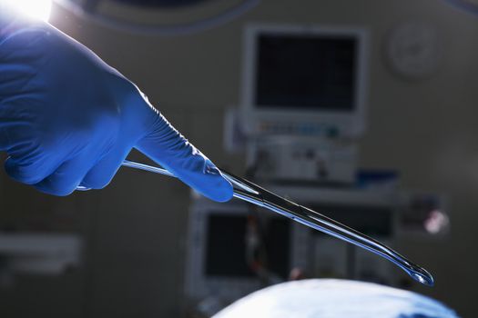 Close-up of gloved hand holding surgical scissors, operating room, hospital