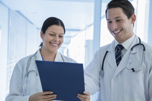 Two smiling doctors looking down at a medical record in the hospital