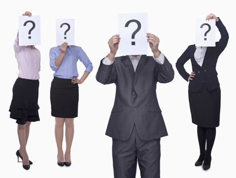 Four business people holding up paper with question mark, obscured face, studio shot