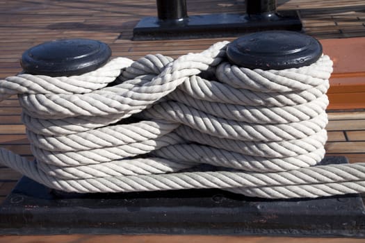 Old ropes around mooring bollard in a deck