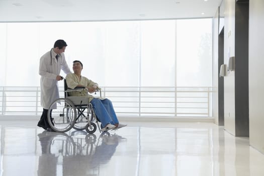 Doctor pushing and assisting patient in the hospital, Beijing, China