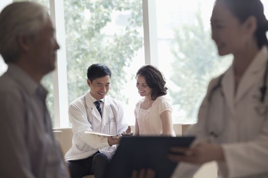 Doctor and patient sitting down and discussing medical record in the hospital, focus on background