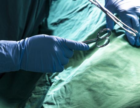 Close-up of gloved hands holding the surgical scissors and working, operating room, hospital