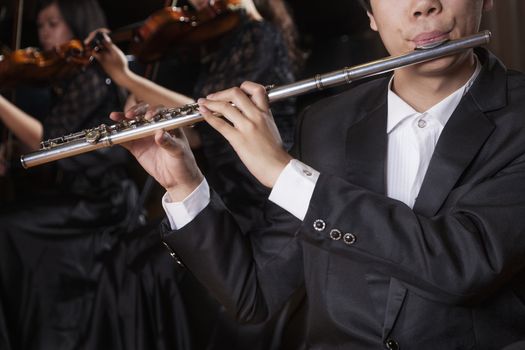 Flautist holding and playing the flute during a performance, close-up