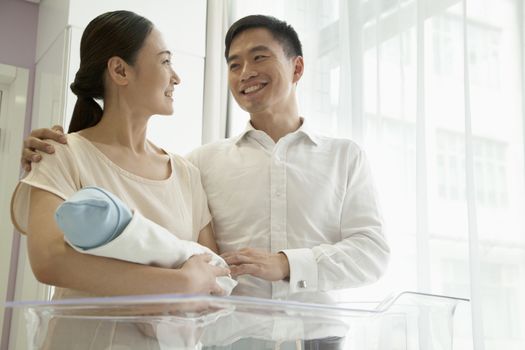 Young happy family holding their newborn in the hospital nursery