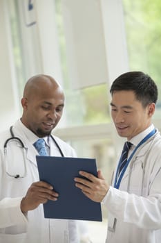 Two doctors looking down and consulting over medical record in the hospital