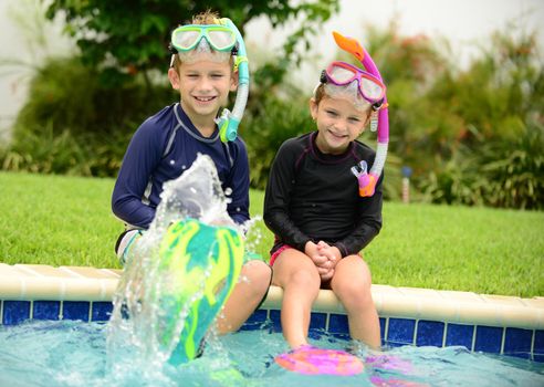 two children splashing water with swimming fins in pool