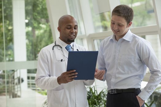 Doctor and patient looking down and discussing medical record in the hospital