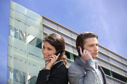 Young business couple using their mobile telephones