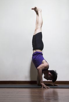 Upside down man doing yoga in a yoga studio, side view