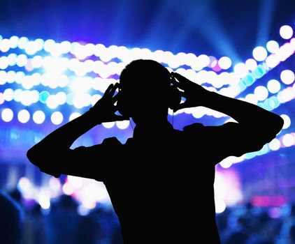 Silhouette of DJ wearing headphones and performing at a night club 