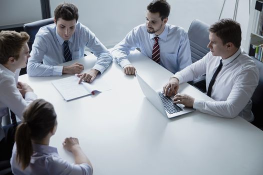 Five business people having a business meeting at the table in the office 