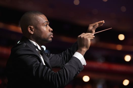 Young conductor with baton raised at a performance 