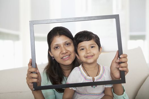 Mother and daughter holding up a picture frame and looking through it