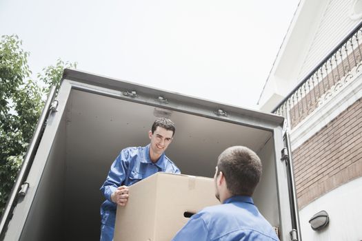 Movers unloading a moving van, passing a cardboard box