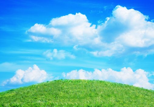 Lush, green hill with blue sky and clouds.