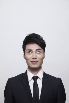 Businessman smiling and looking up, studio shot