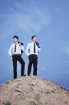 Two young businessmen standing on the top of the hill in the desert