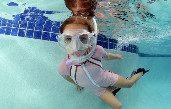 young child swimming with goggles and snorkel
