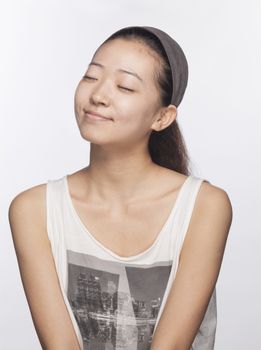 Smiling young woman with eyes closed, studio shot