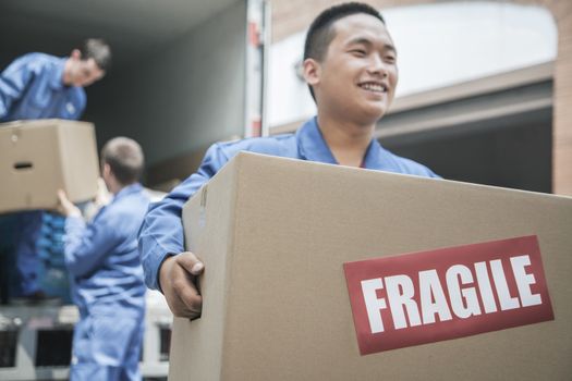 Movers unloading a moving van and carrying a fragile box