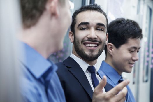 Three businessmen standing in a row and talking on the subway