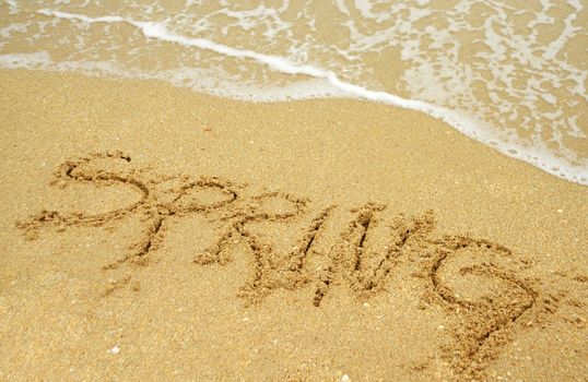 A warm tropical beach for spring break concept and spring written in the sand 