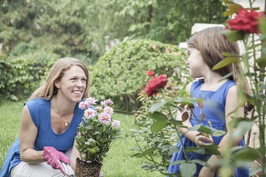 Smiling mother and daughter gardening flowers in the garden