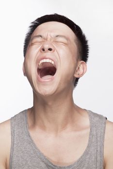 Portrait of young man screaming, mouth open, studio shot