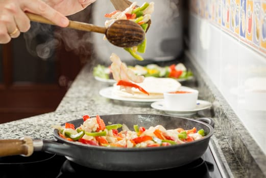 Closeup of man cooking vegetables and chicken for a mexican food in a black pan
