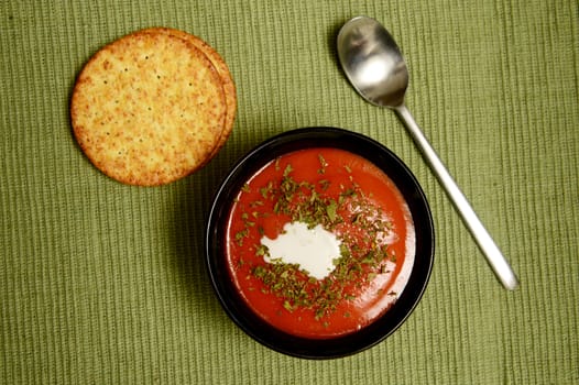 tomato soup on green with healthy whole grain crackers