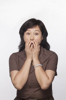 Portrait of shocked and surprised woman with hands covering her mouth, studio shot