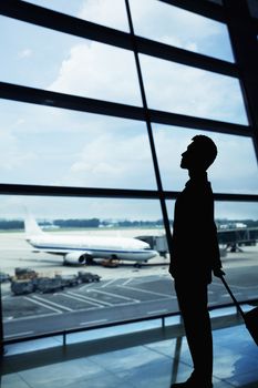 Silhouette of businessman waiting in the airport and looking out the window