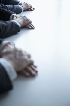 Close-up on folded hands of business people at the table during a business meeting