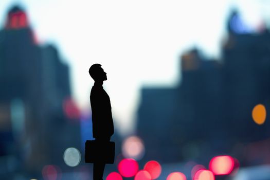 Silhouette of businessman holding a briefcase with blurred city lights behind him