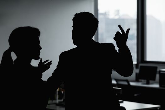 Silhouette of two business people gesturing and arguing in the office