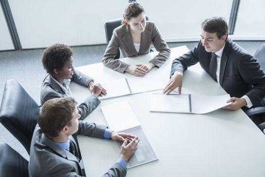 Four business people sitting around a table and having a business meeting, high angle view 